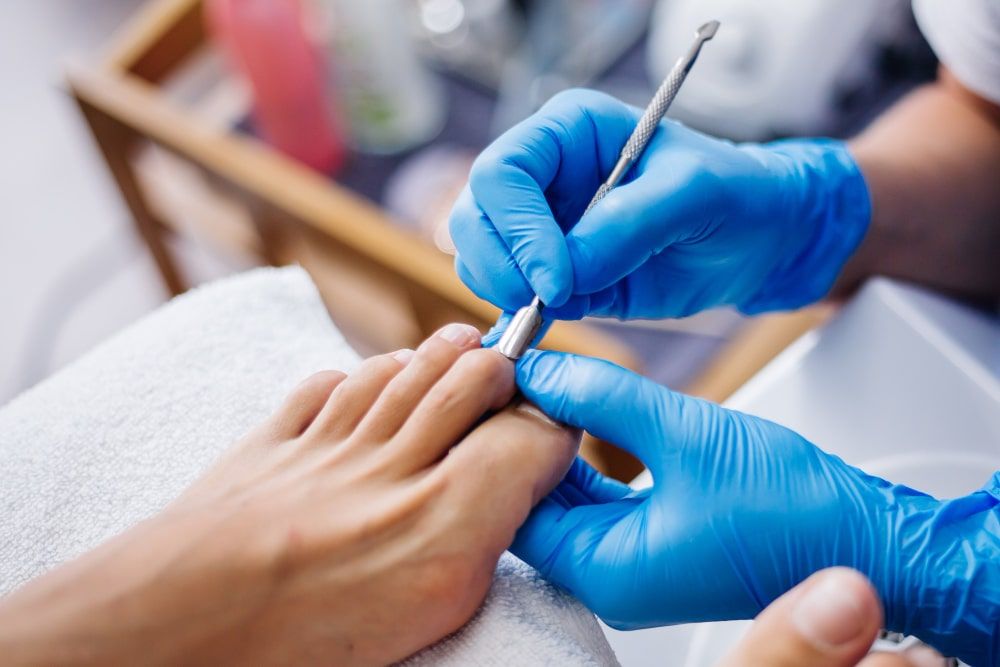 pedicure-process-home-salon-pedicure-foot-care-treatment-and-nail-the-process-of-professional-pedicures-master-in-blue-gloves-make-pedicure-min tratamiento para uña encarnada